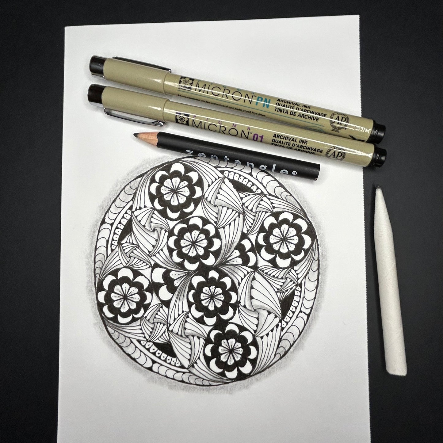 Zentangle design on paper with Micron pens on a dark surface