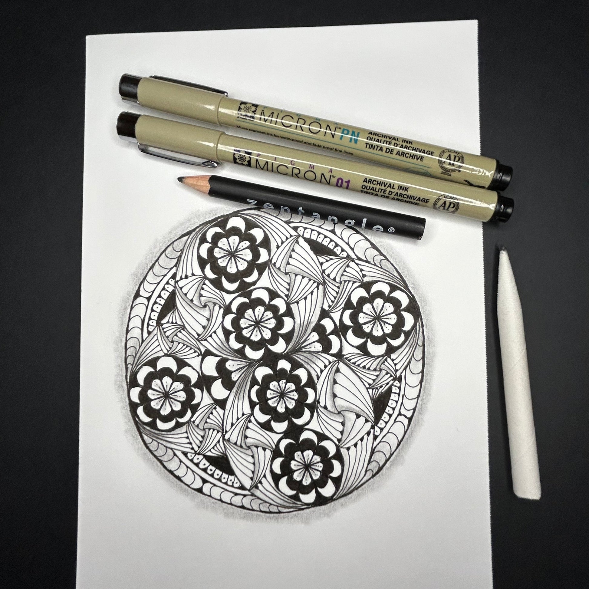 Zentangle design on paper with Micron pens on a dark surface
